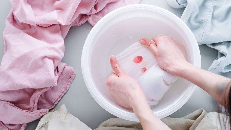 Hand washing stained white clothes after color bleeding.