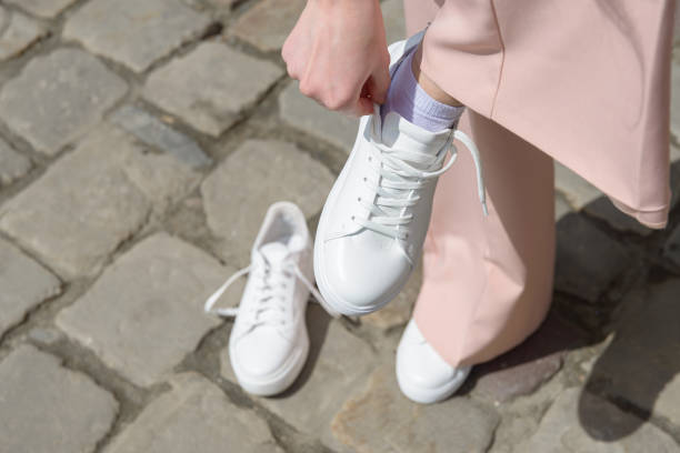 Person wearing white sneakers outdoors.