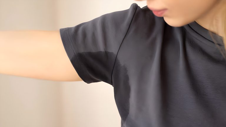 Woman with a sweat stain under the arm of her dark t-shirt.