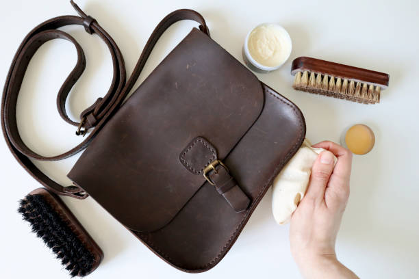 Polishing a brown leather bag with cleaning tools.