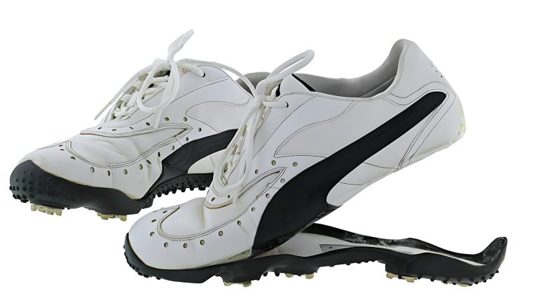 A pair of old and dirty Golf shoes in black and white with split rubber sole, isolated on white