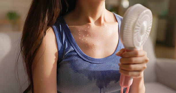 Woman sweating and using a handheld fan.