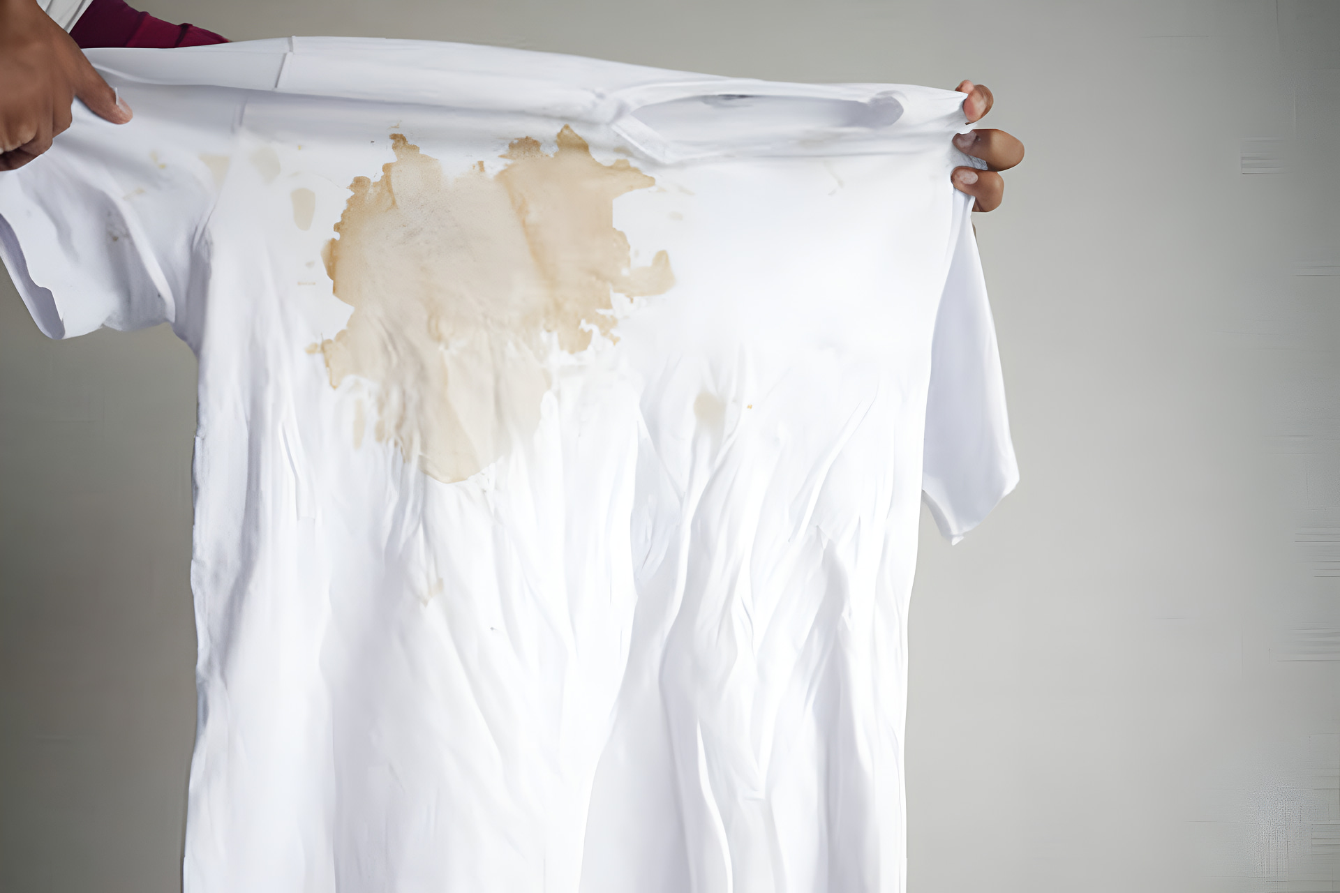 women holding a white color dirty white shirt, showing making stain.